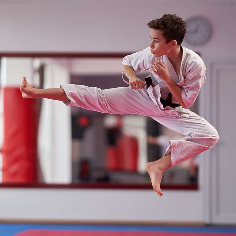 teen martial arts student performing flying side kick