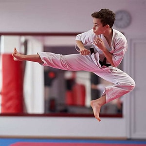teen sdss martial arts student performing a flying side kick